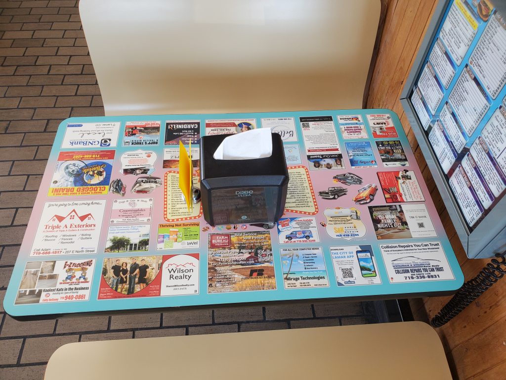 A photo of a booth with tabletop ads and 1950s car retro design at BJ's in Lamar, Colorado.